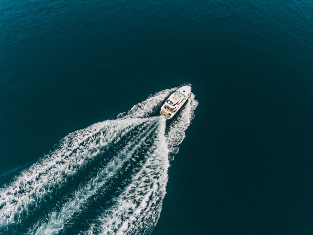 Aerial view of boat with Whitewater wake on dark blue ocean